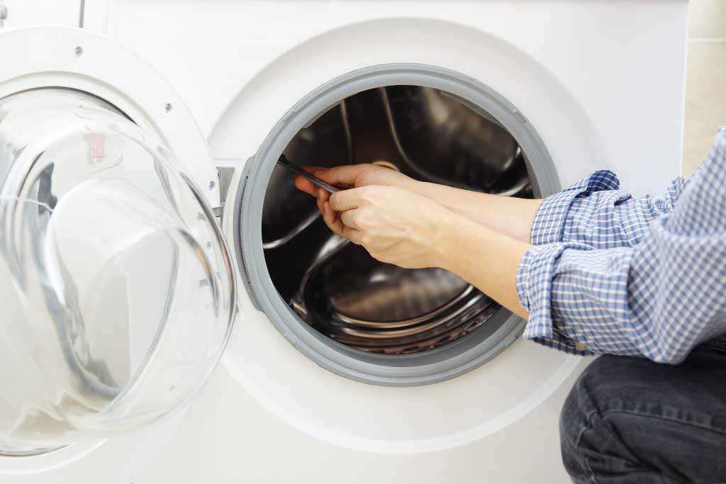 An appliance repair technician repairing a clothes dryer