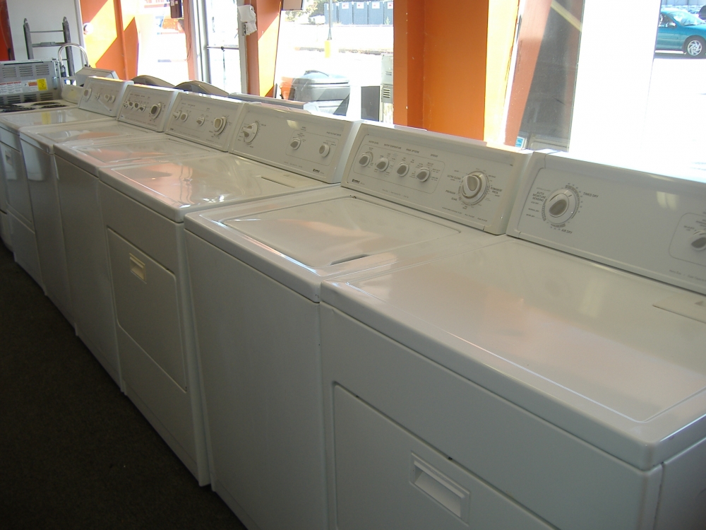 A row of used washers and dryers in a store